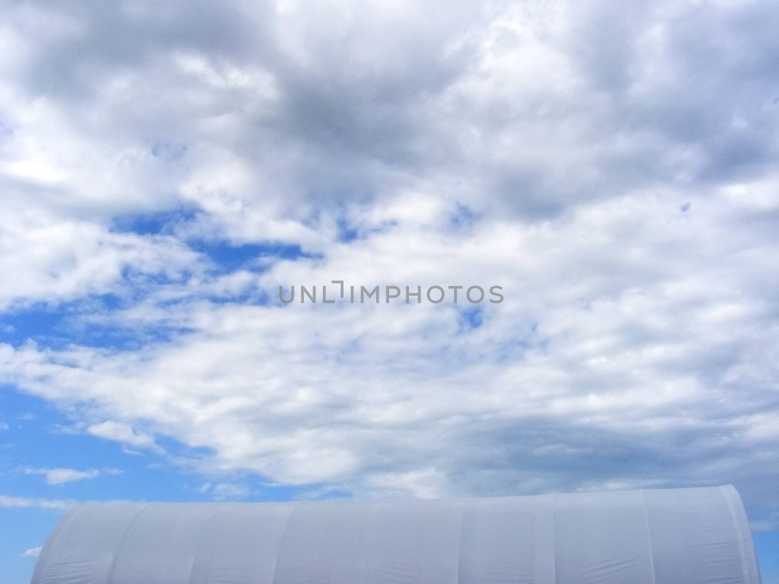 Industrial temporary shelter on a cloudy summer sky.