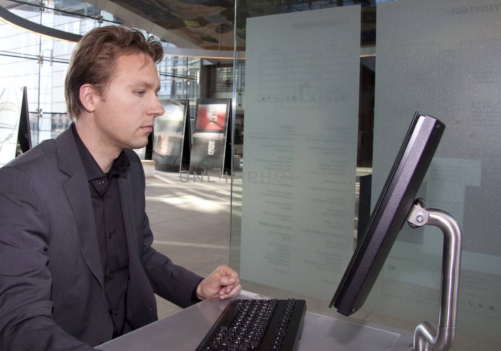 A young executive is standing and using the computer in the in a business lounge