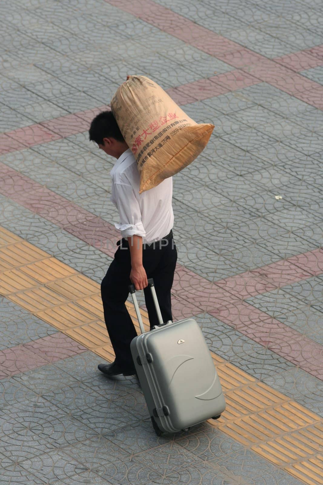 Chinese man carrying his luggage and a paper bag (with Chinese characters) in the street of Xi'an
