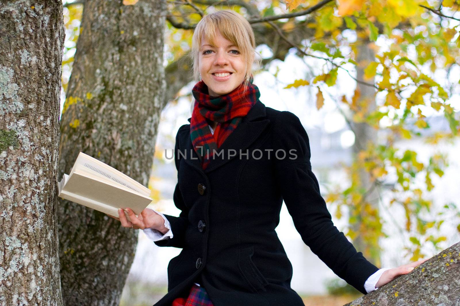 Young student girl is studying outside near the tree