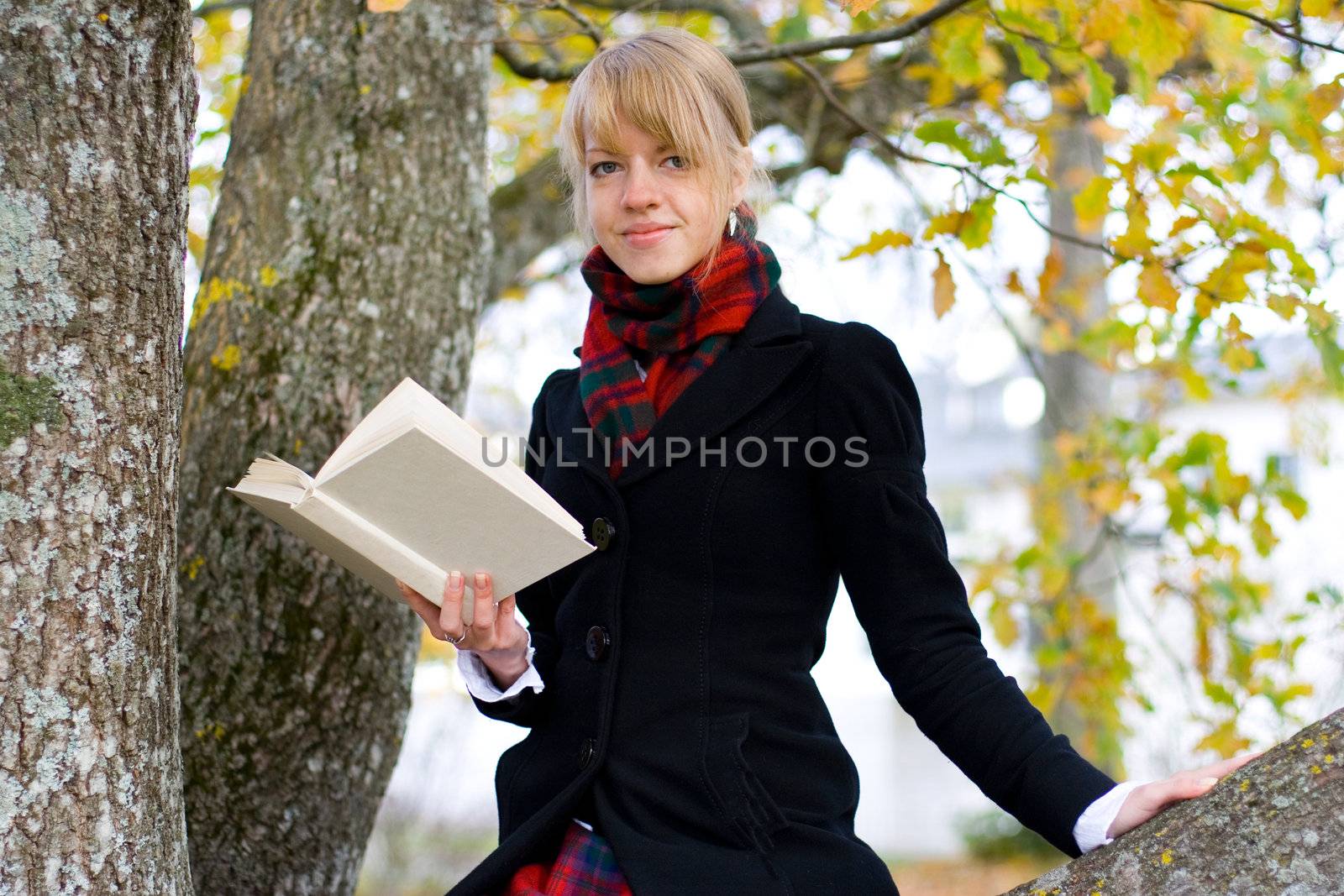 Young student girl is studying outside near the tree