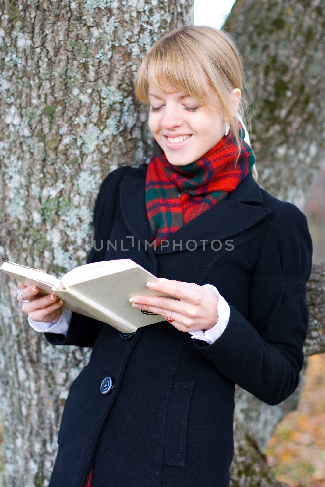 Young student girl is studying outside near the tree