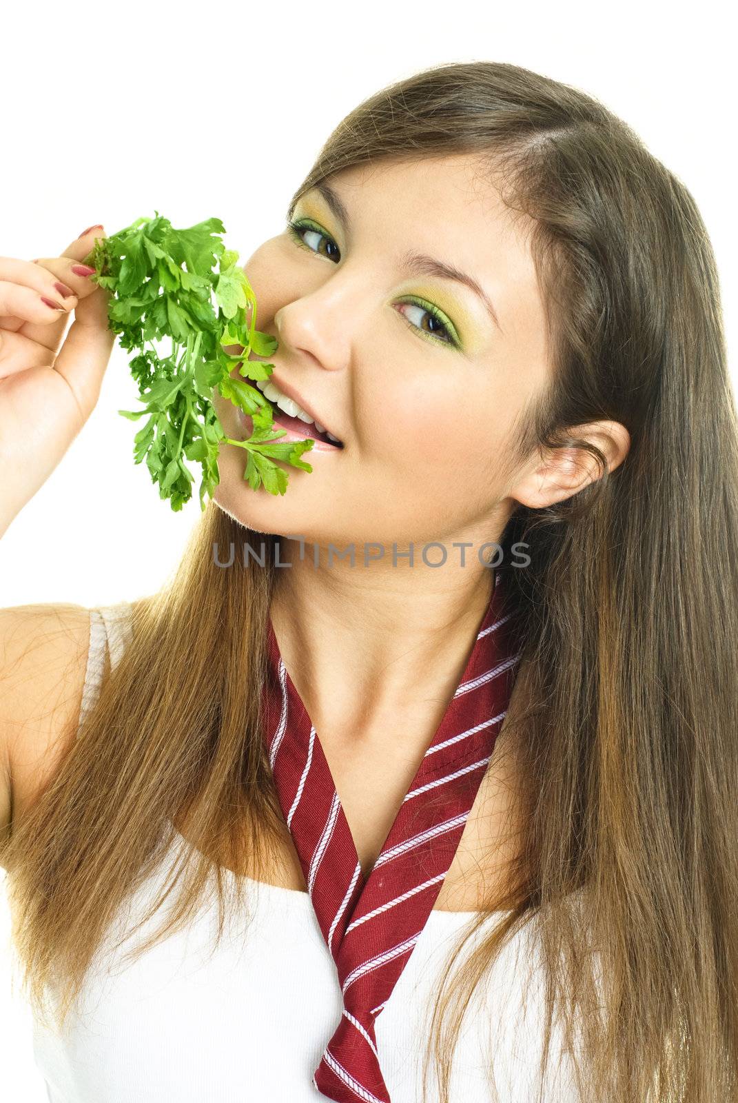 portrait of a happy beautiful brunette girl eating fresh green parsley