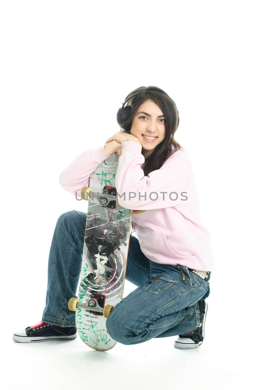 happy teenage girl wearing earphones and holding a skate board