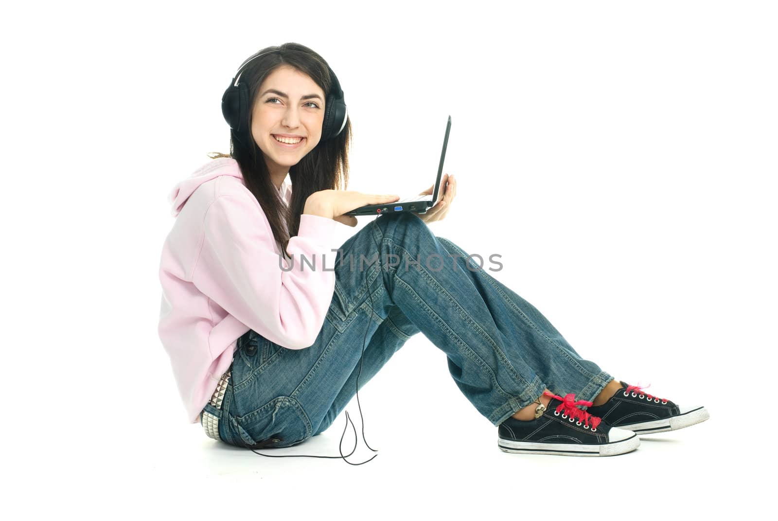 beautiful teenage girl wearing earphones  sitting on the floor with a laptop  