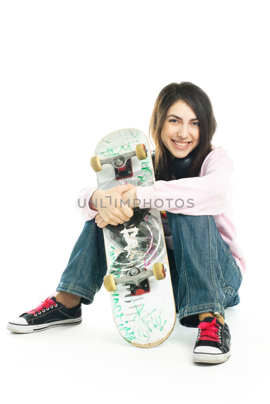 happy teenage girl wearing earphones and holding a skate board