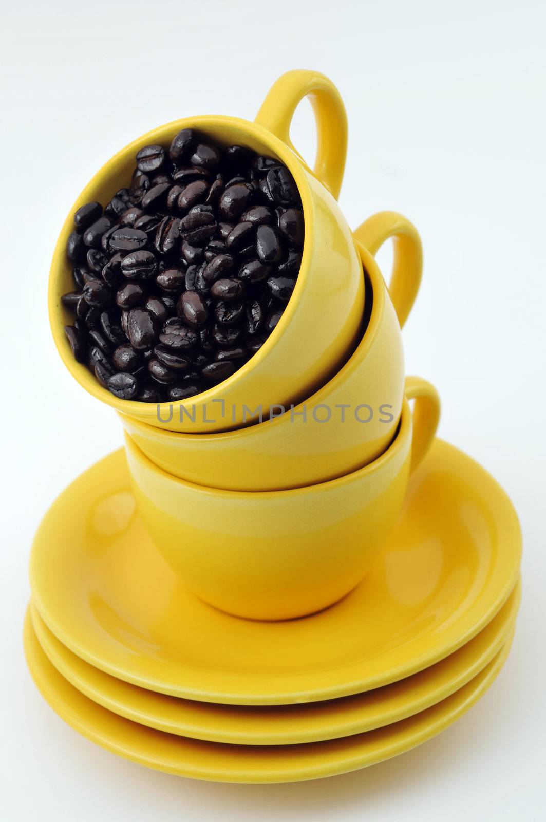 Three yellow cups full with coffe beans isolated on white