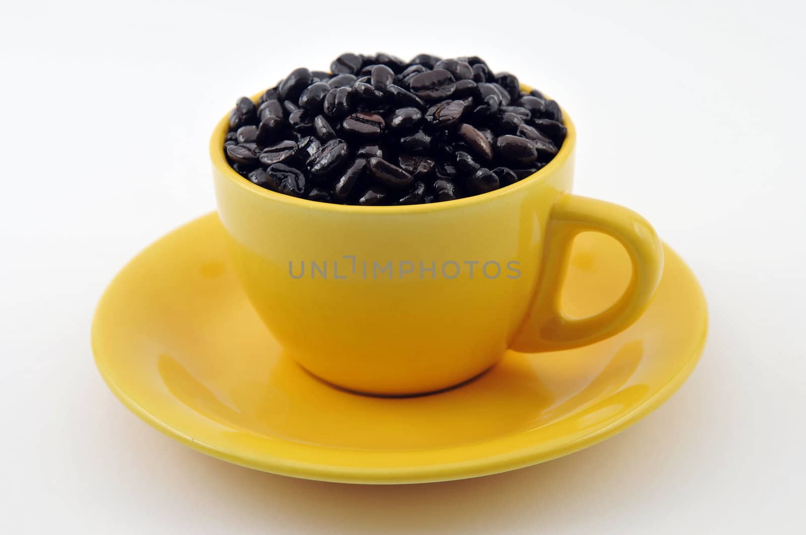 Yellow cup full with coffe beans isolated on white