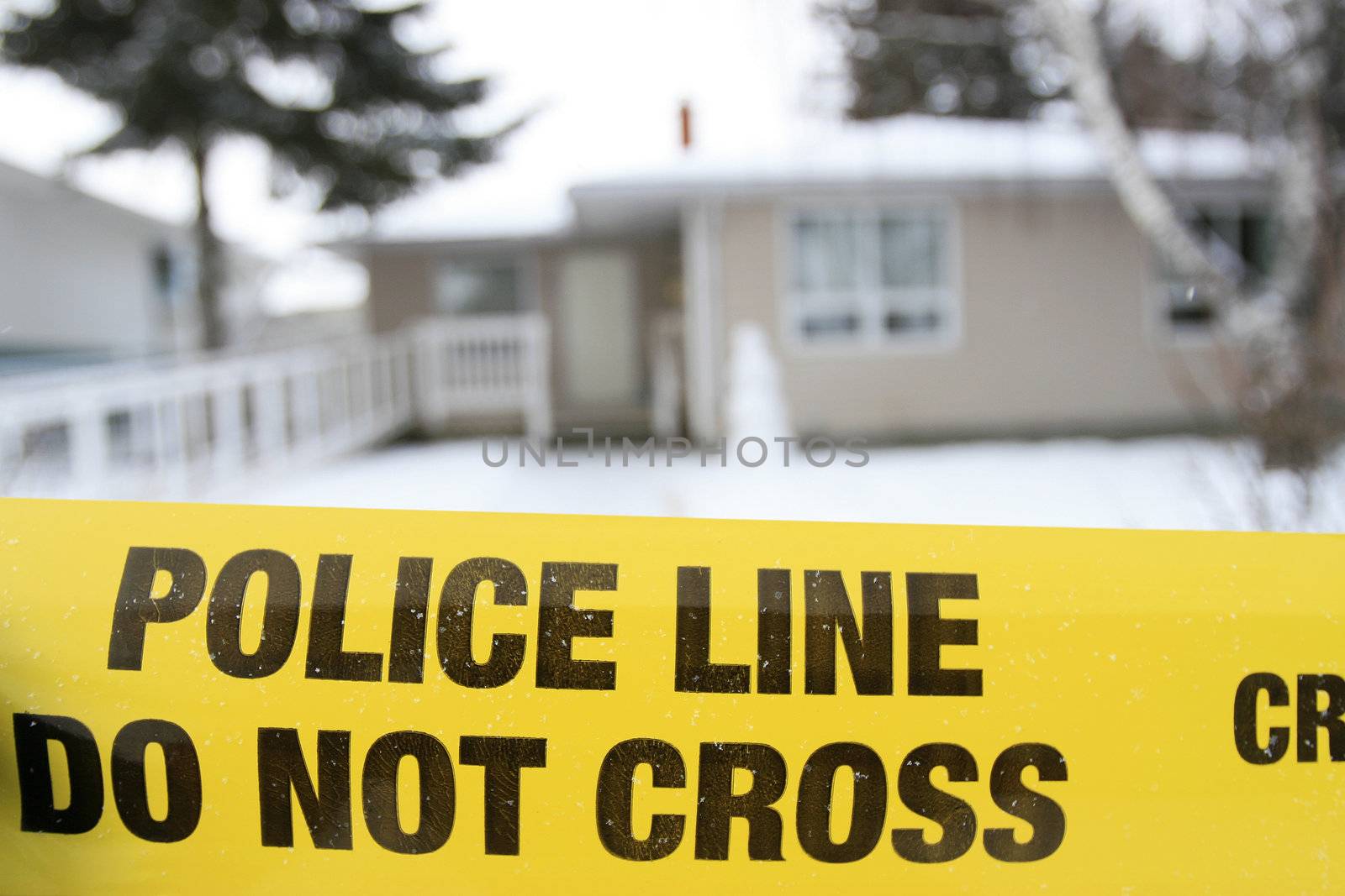A yellow police line in front of a house under investigation.