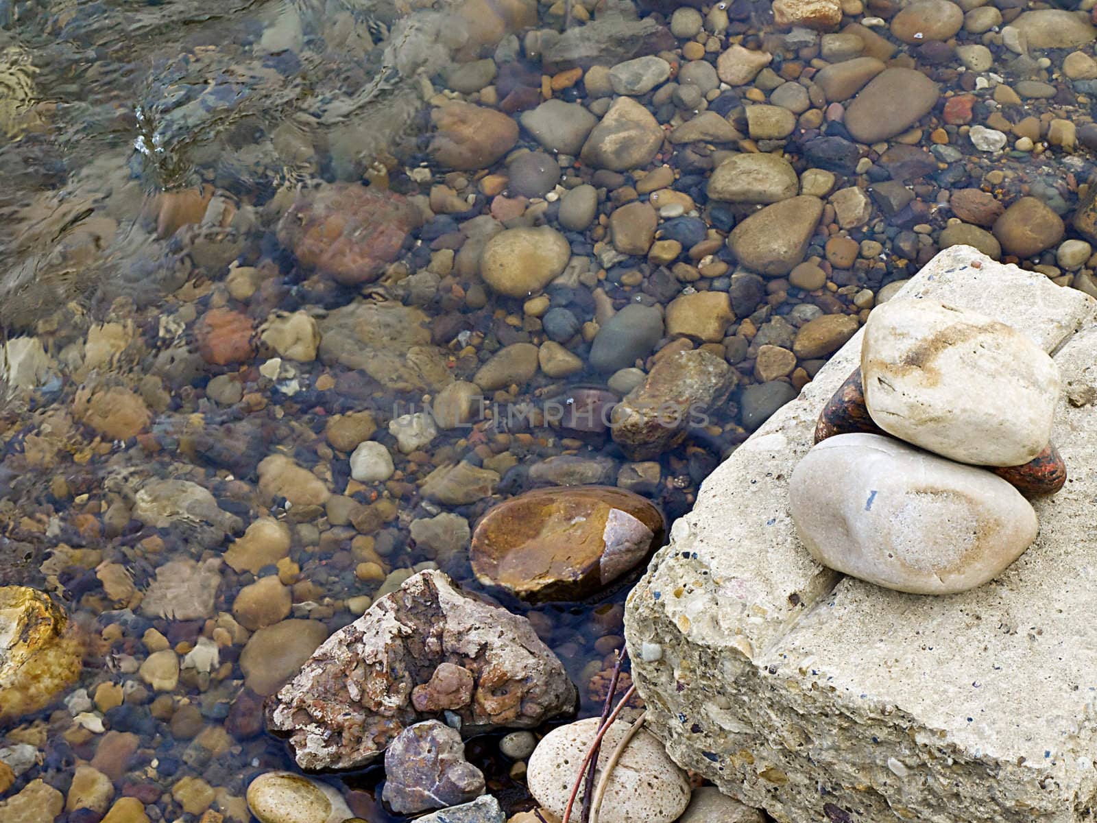 Stones on a block of cement near a icy river bank.