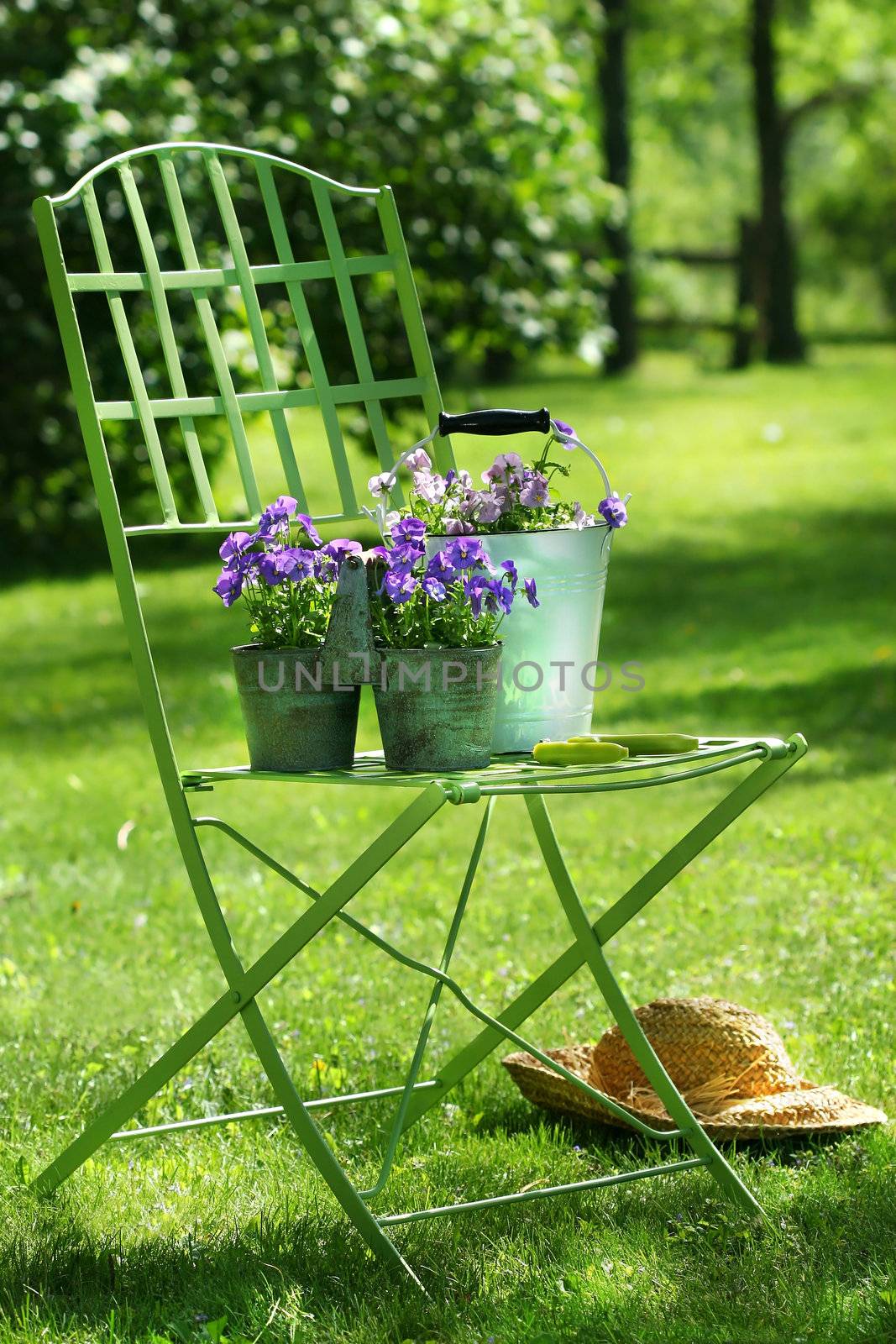 Green garden chair with straw hat