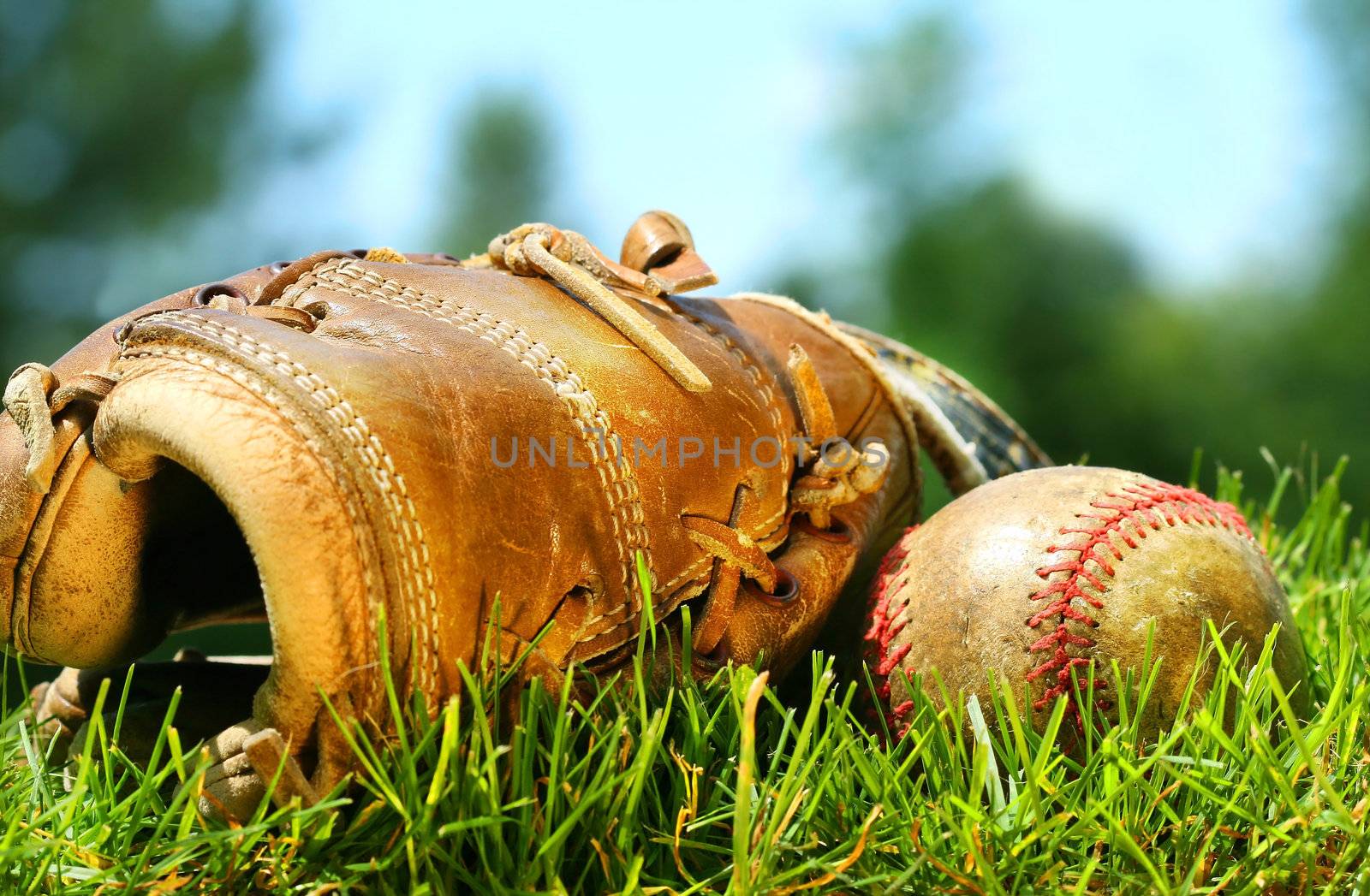 Old baseball glove and ball on the grass by Sandralise