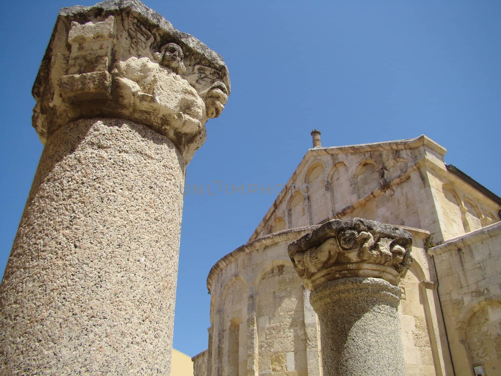 roman pillar in fron of the 11th-century, three-naved Basilica of San Gavino, which was built using only precious hardstones like marble, porphyry and granite, is the largest Romanesque church in Sardinia.