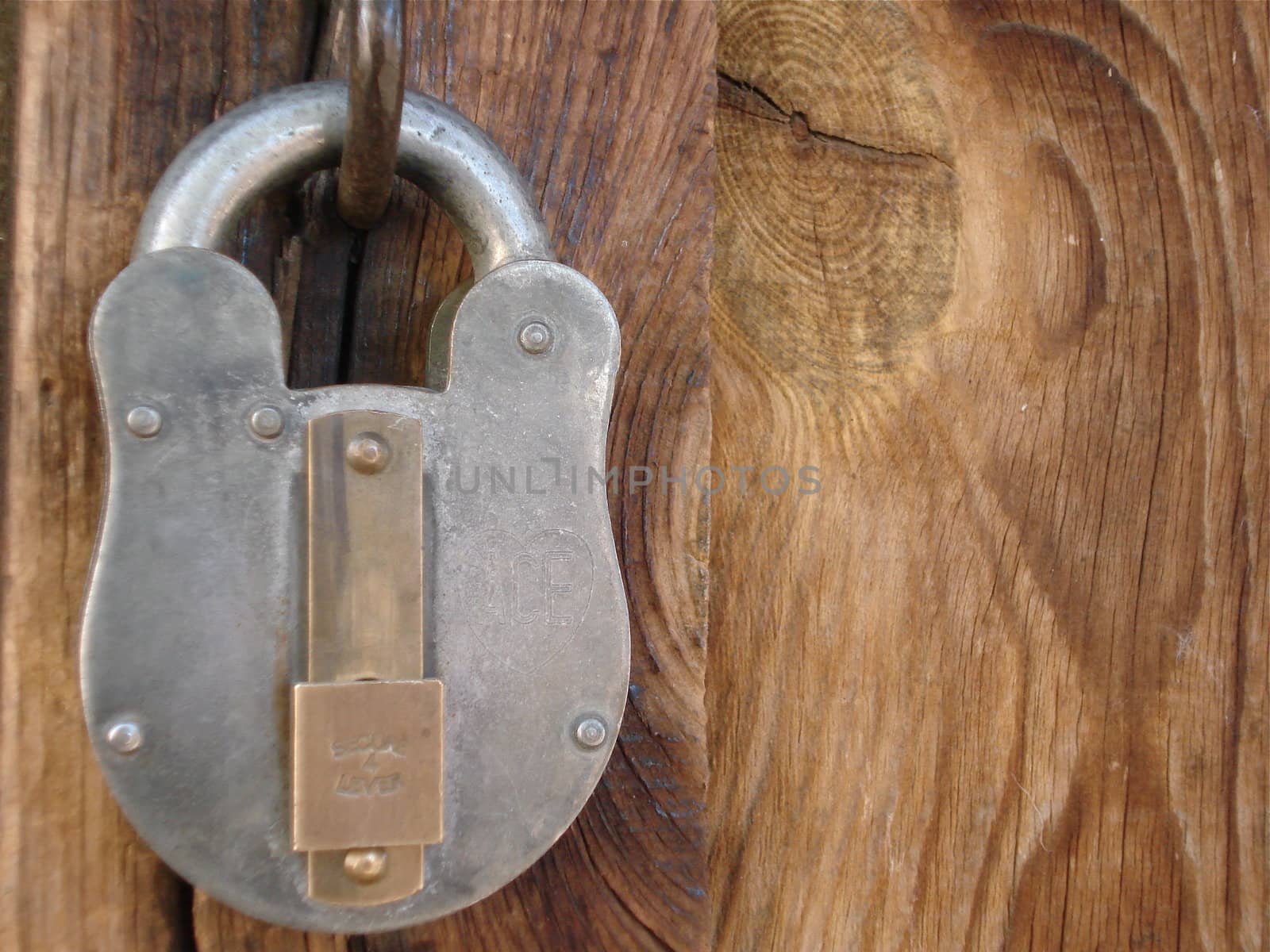 A metal lock hangs on an old barn door.