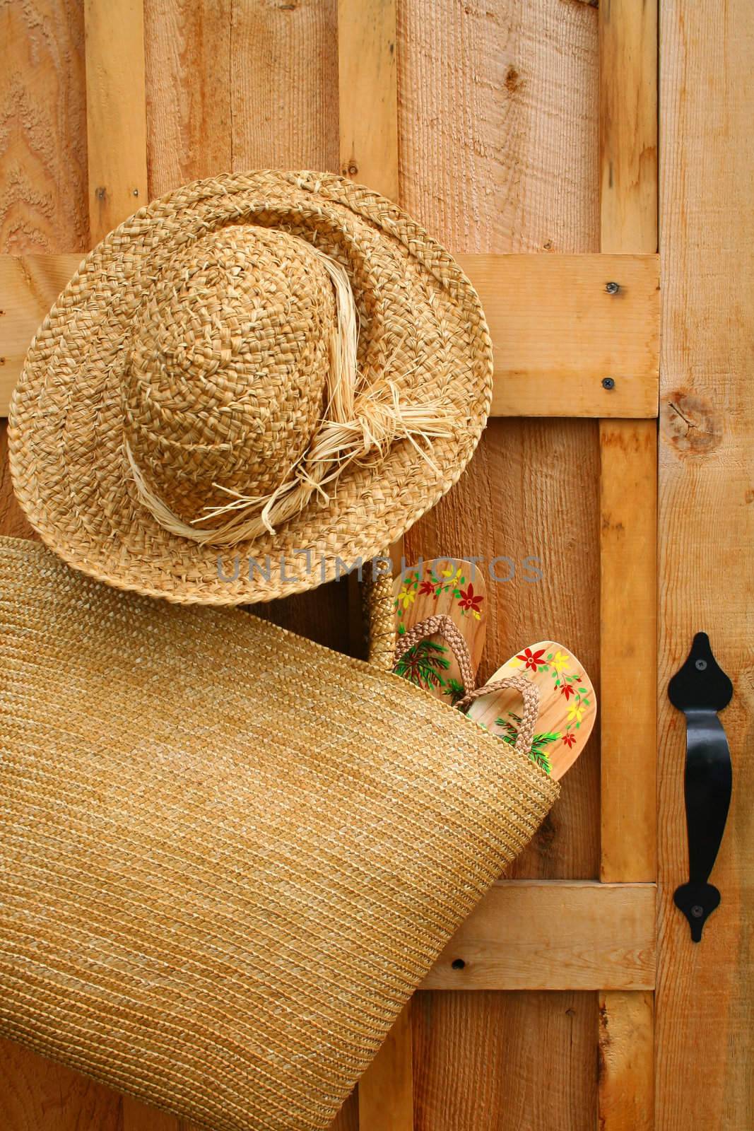Pair of sandals hanging out of wicker purse with sun hat