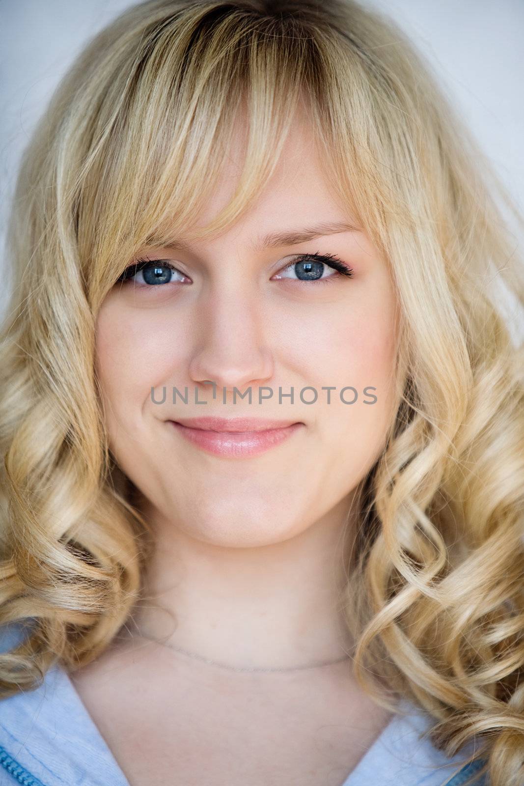Portrait of the smiling blond girl with blue eyes 
