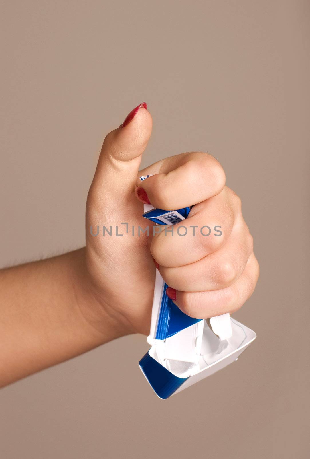 closeup of the hand of a young woman rumpling a pack of cigarettes 