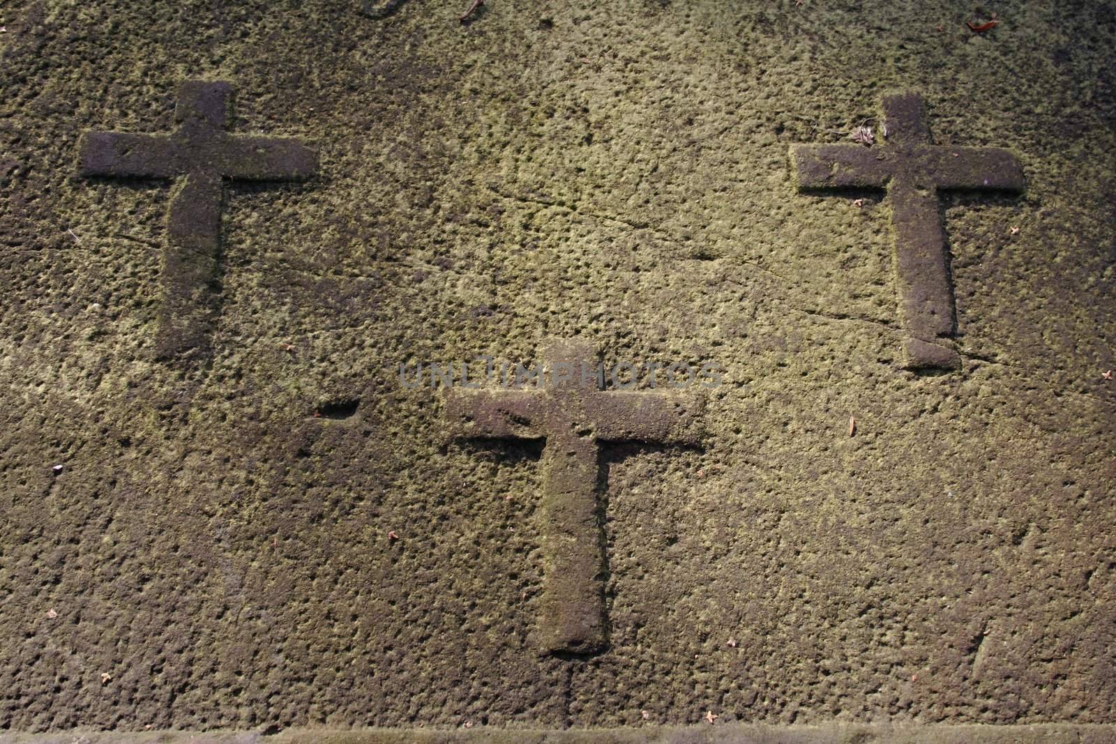 Three carved crosses on a very old weathered gravestone covering a grave in an 18th century churchyard (Hamburg, Germany).