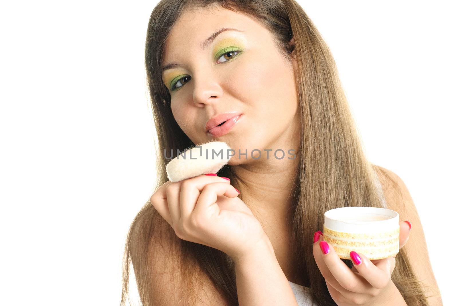 beautiful young woman applying powder with a sponge and blowing on it