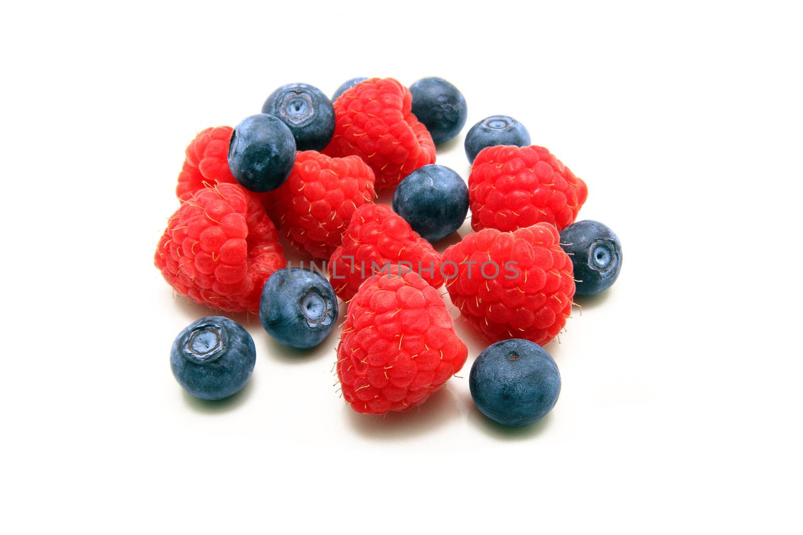 A bunch of plump delicious raspberries and blueberries isolated on white