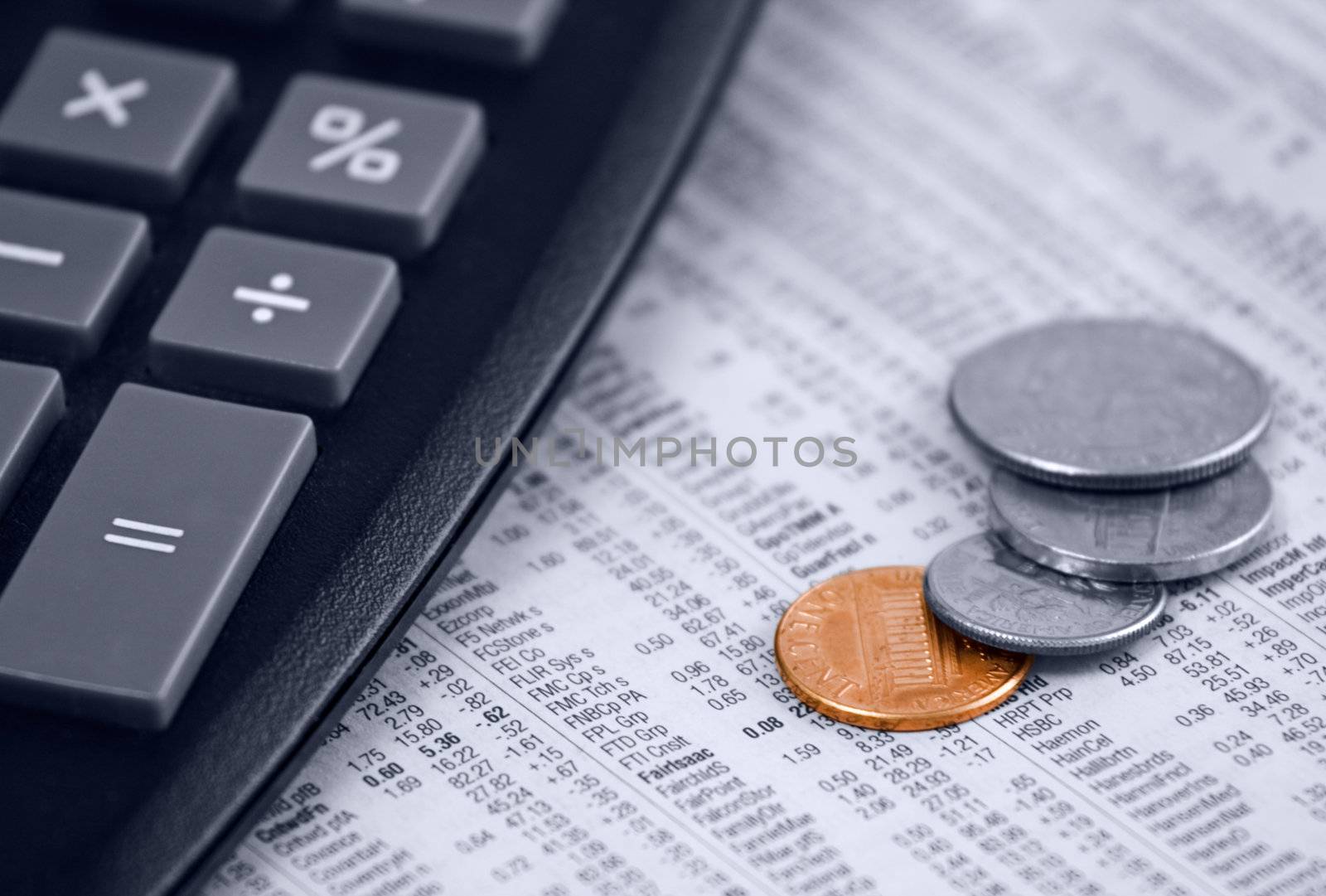 Calculator and US coins on a stock quote background, shallow depth of field, focus on colored penny