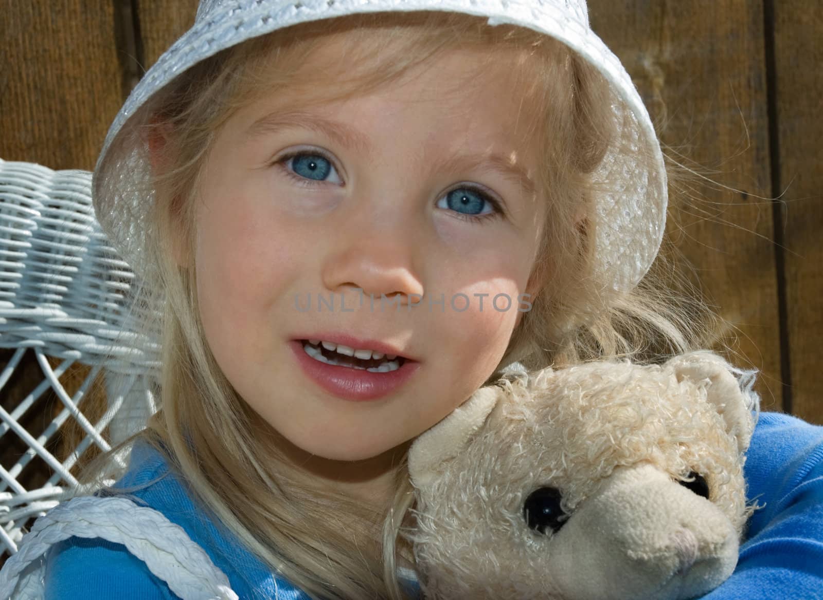 Cute country belle girl with a well loved teddy bear, blue eyes, sunny summer day