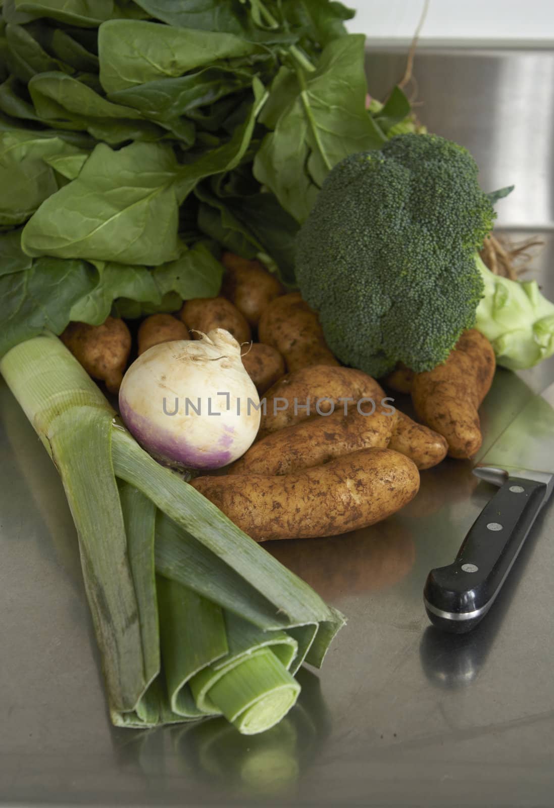 Still life of vegetables on stainless steel bench with knife