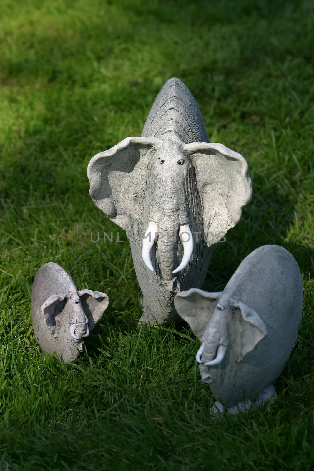 Three clay elephants on a grass