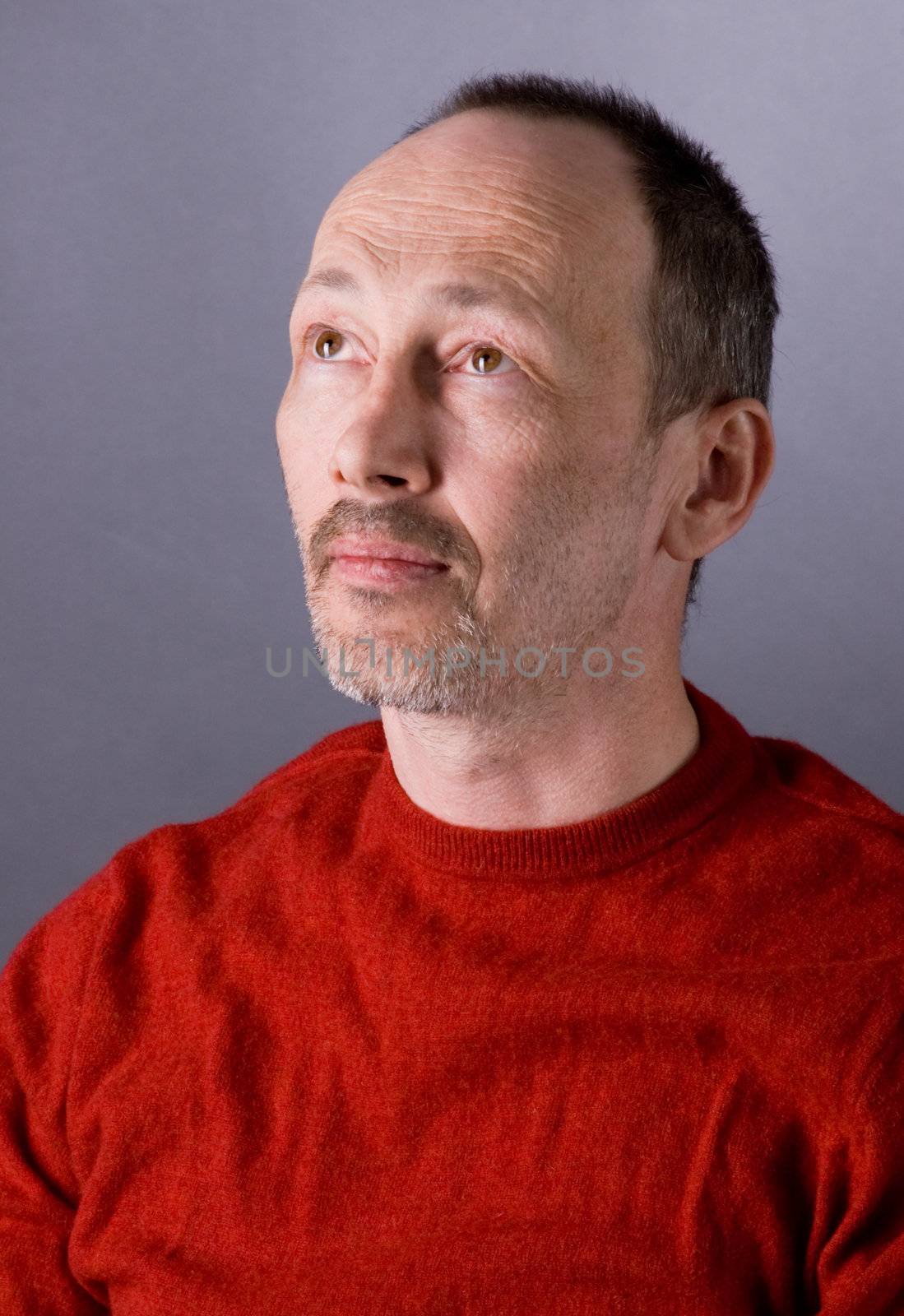 The man in a red sweater sits on a chair