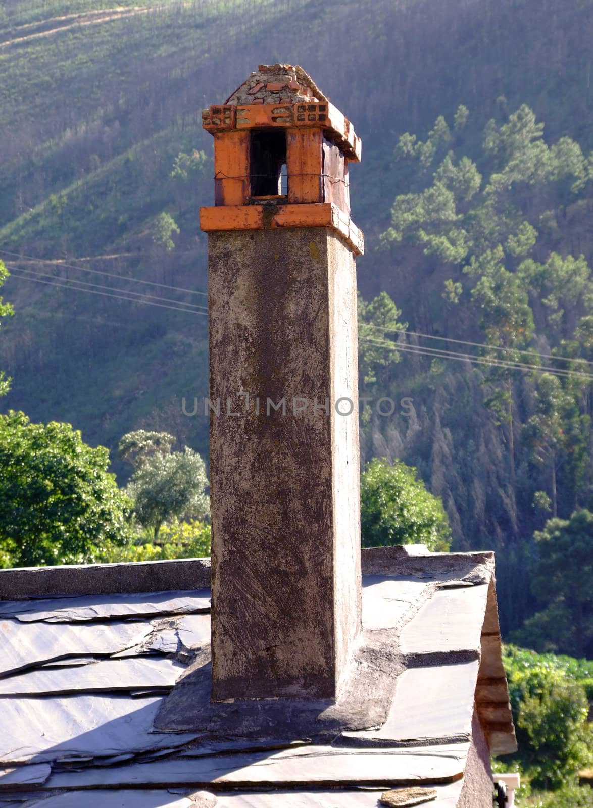 Old rustic chimney on top of srone roof
