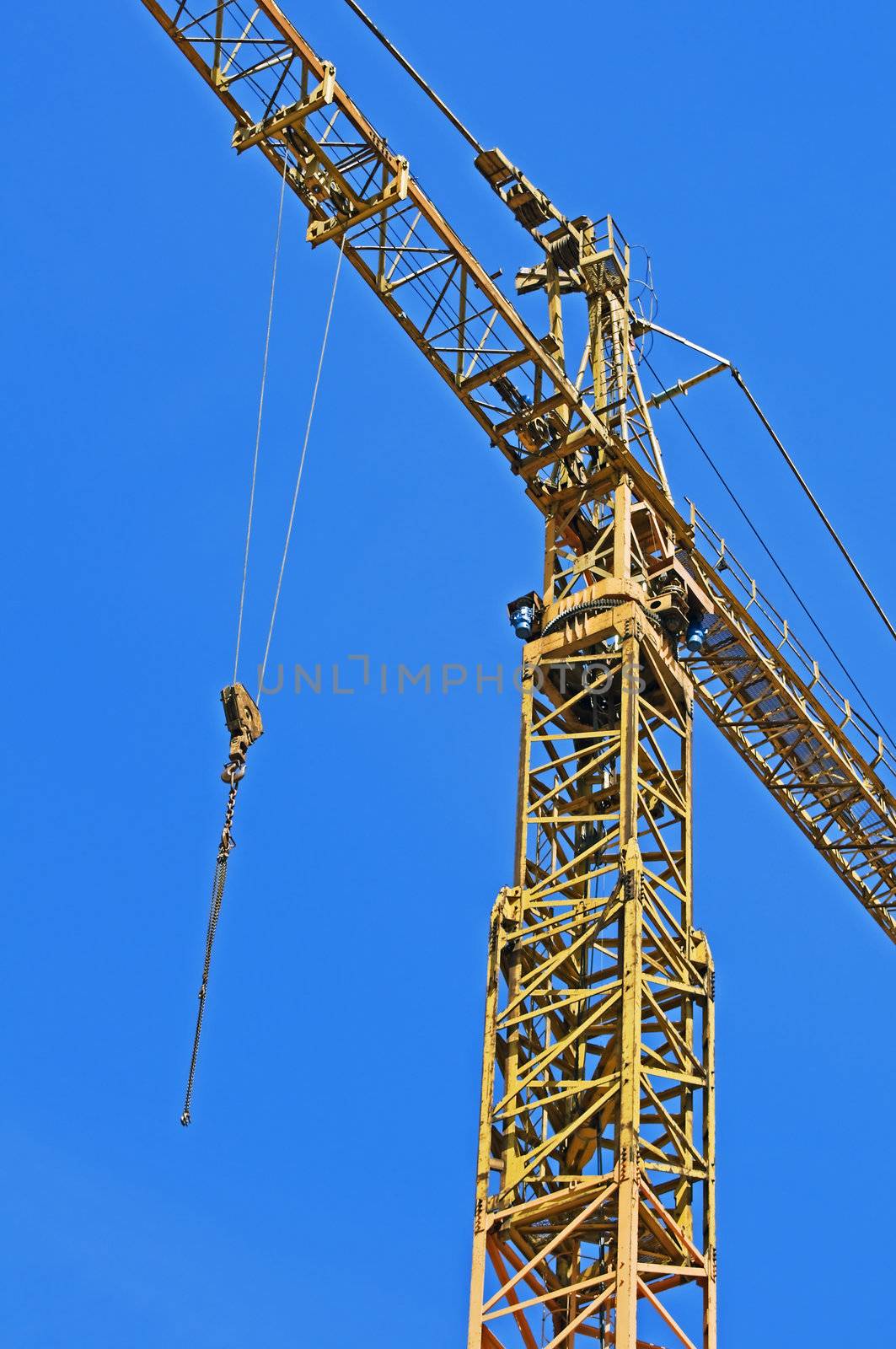 Detail of a yellow crane with hook against a blue sky