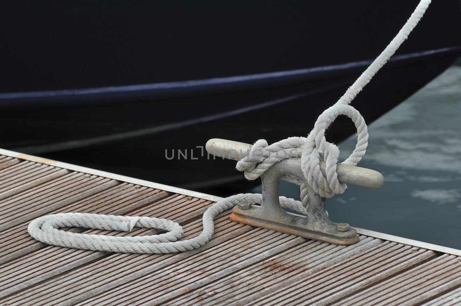 Detail of a rope tied up to bitt of a jetty
