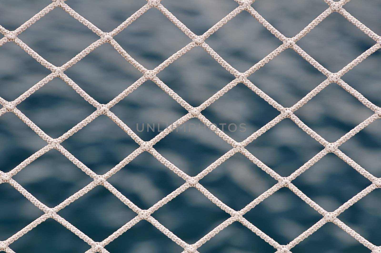 Close-up of net against a dark blue sea