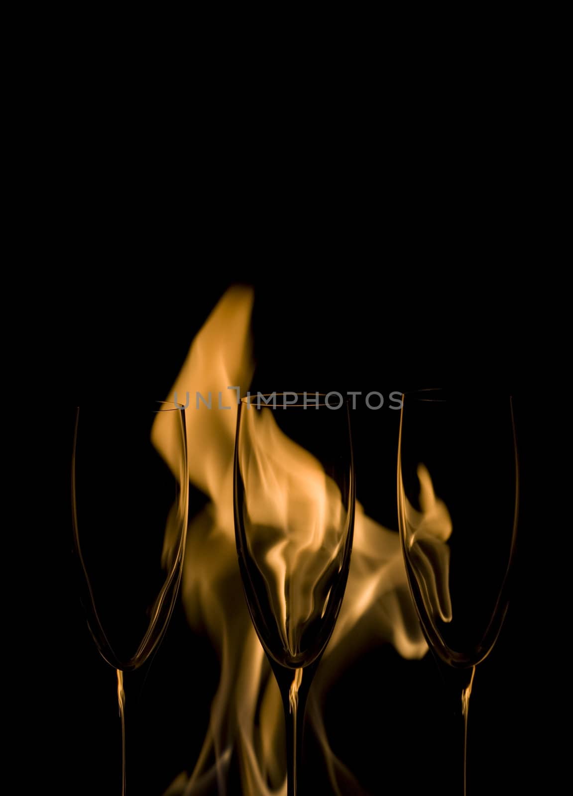 Three Crystal glasses and fire isolated on black  