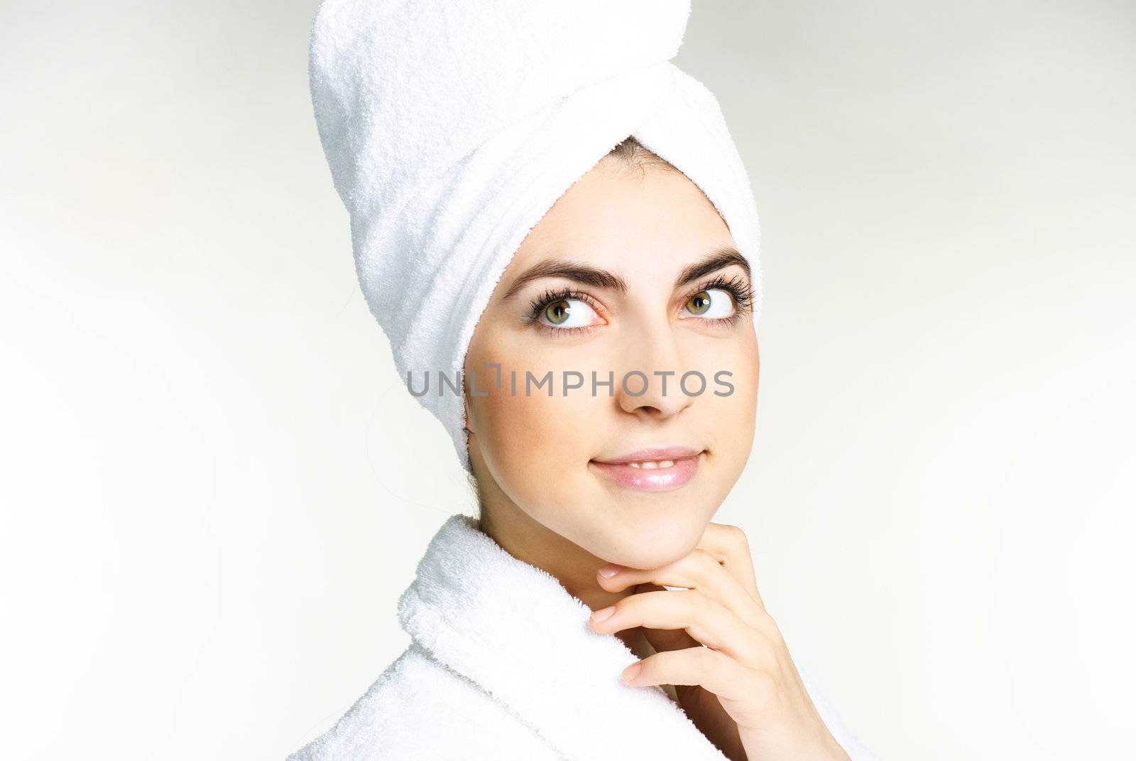 portrait of a pretty girl wrapped into the white towel and wearing a white dressing gown