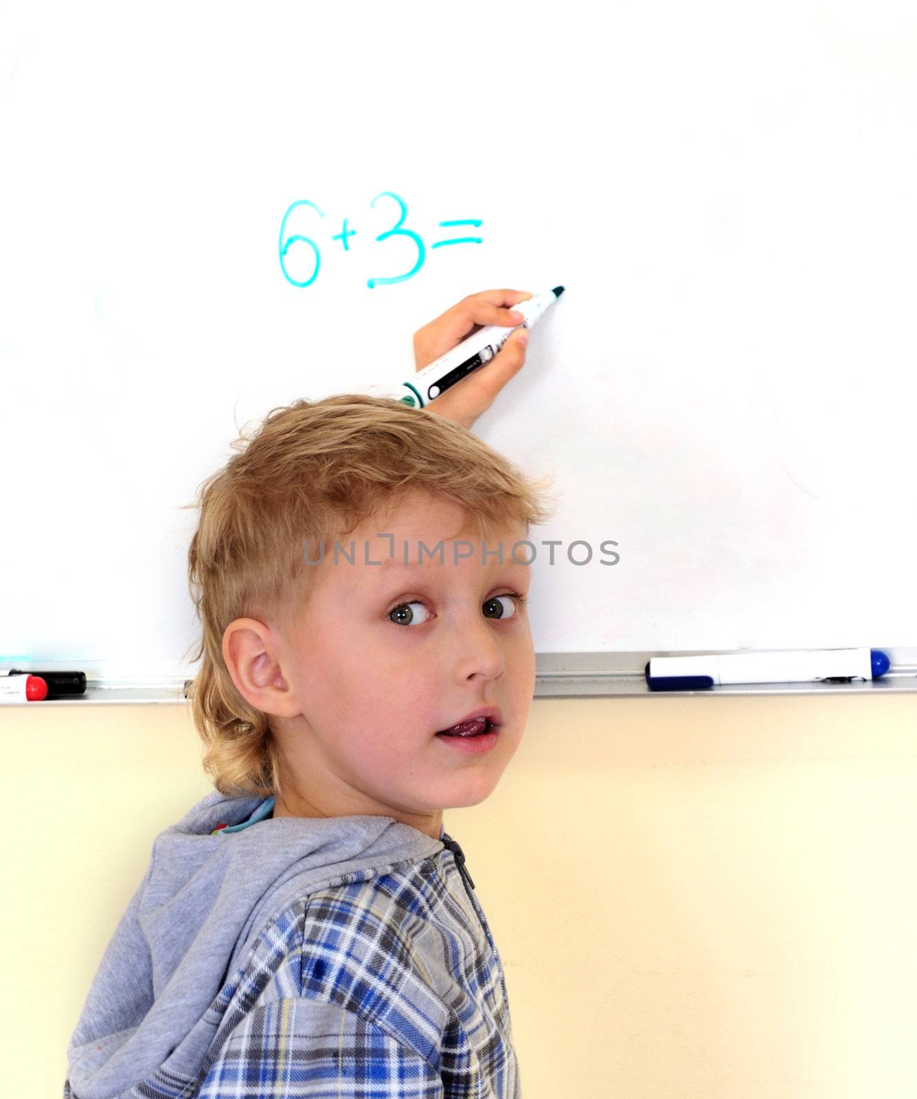 left-hander little boy solving an exercise on a desk
