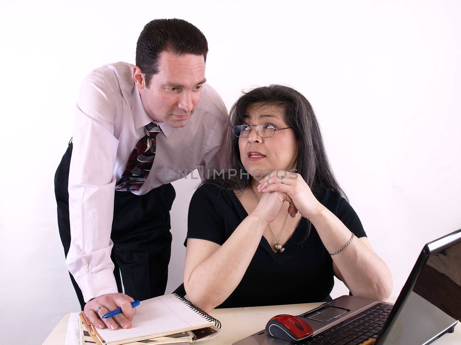 A male and female working together in the office at the computer. Isolated against a white background.