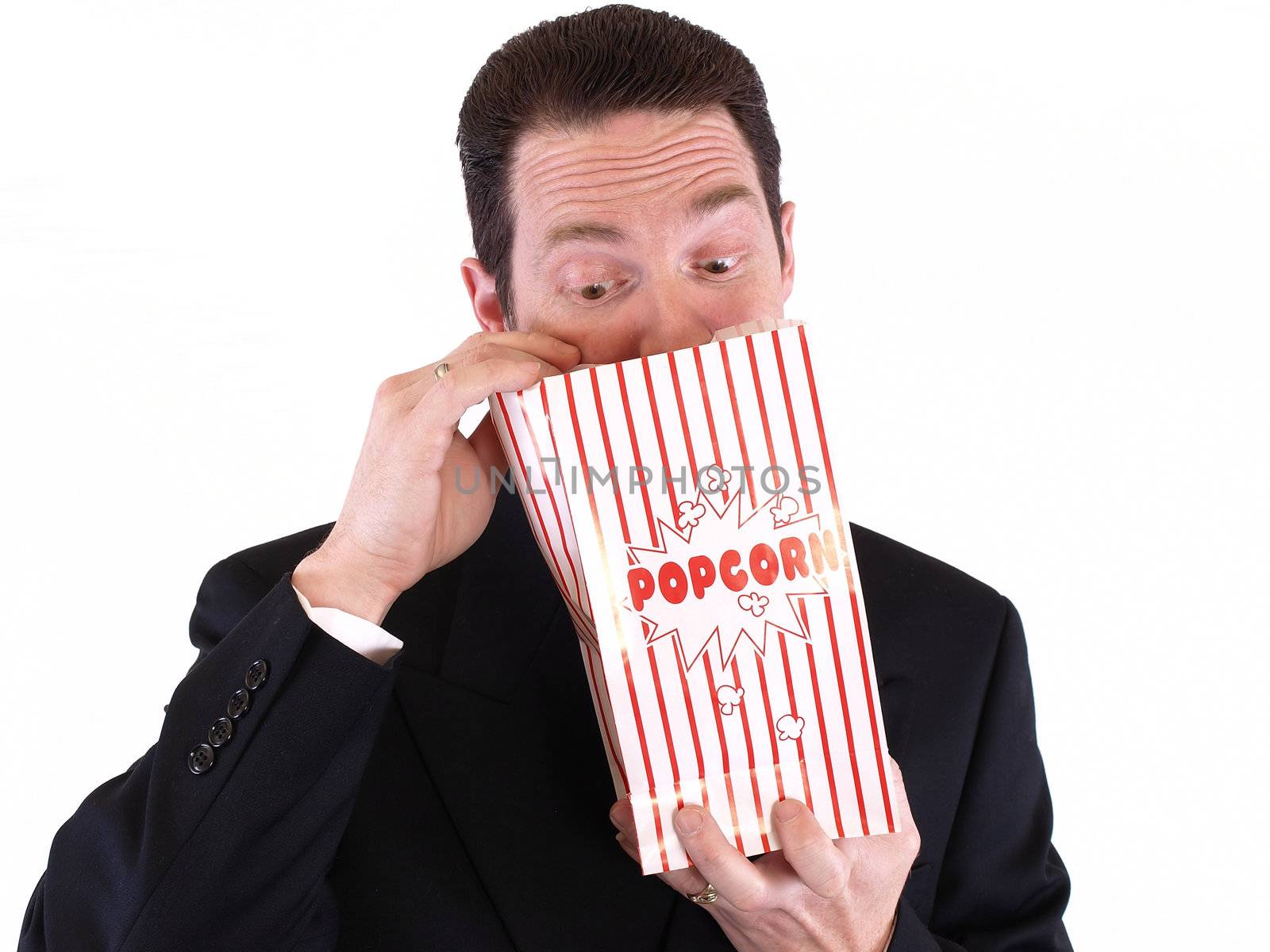 Adult male in a suit holding a popcorn bag and looking in. Isolated on a white background.