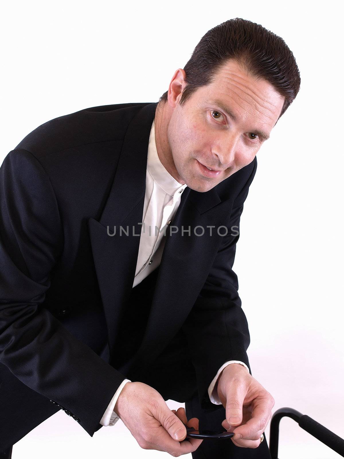 A standing man leans down on one knee to check an incoming text message on his cell phone.