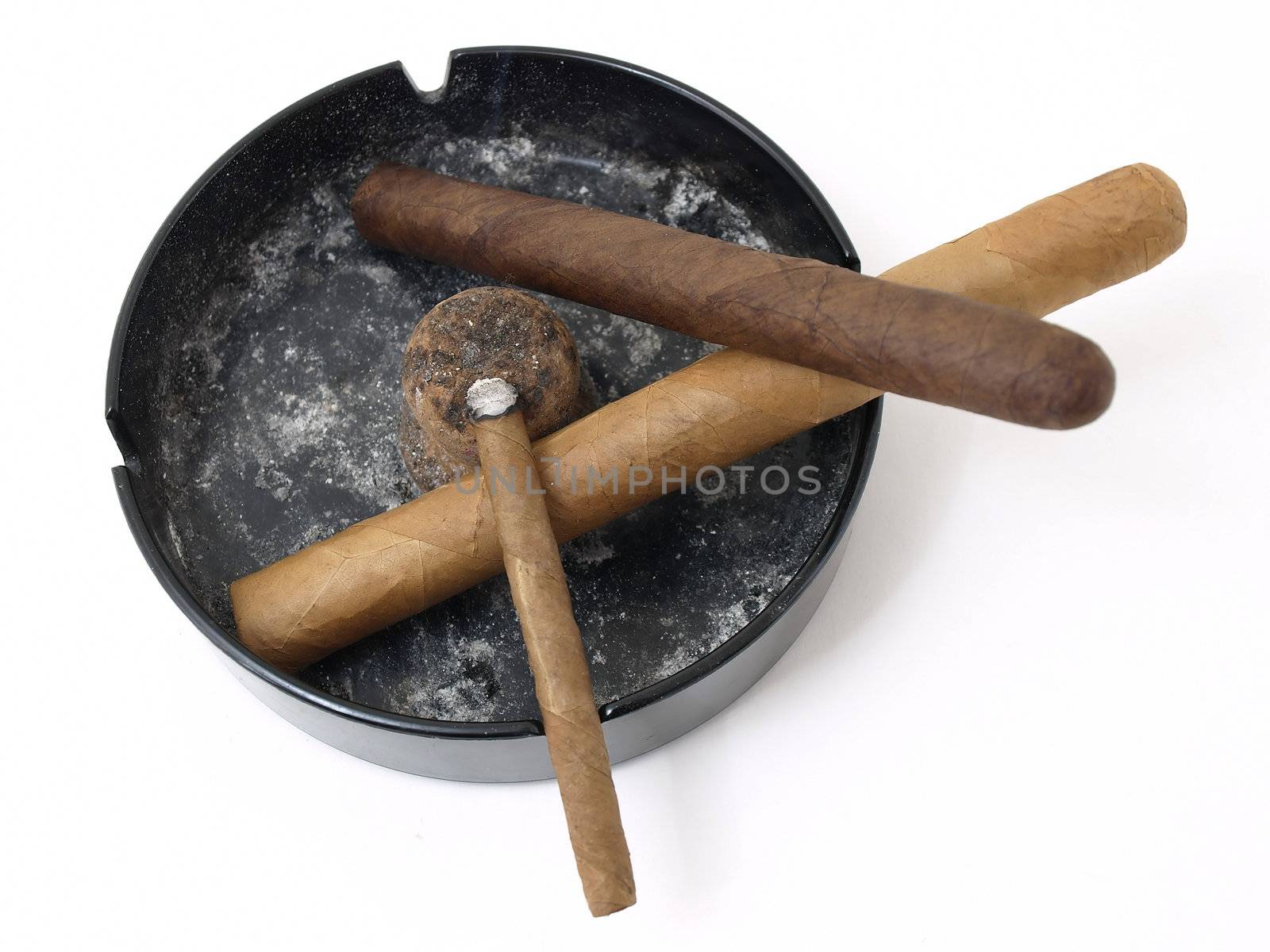 Three cigars resting in a dirty ashtray isolated on a white background.