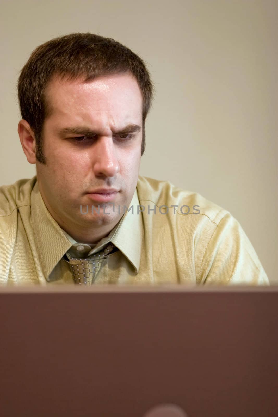 A young business man is looking concerned at what he is seeing on his laptop screen.