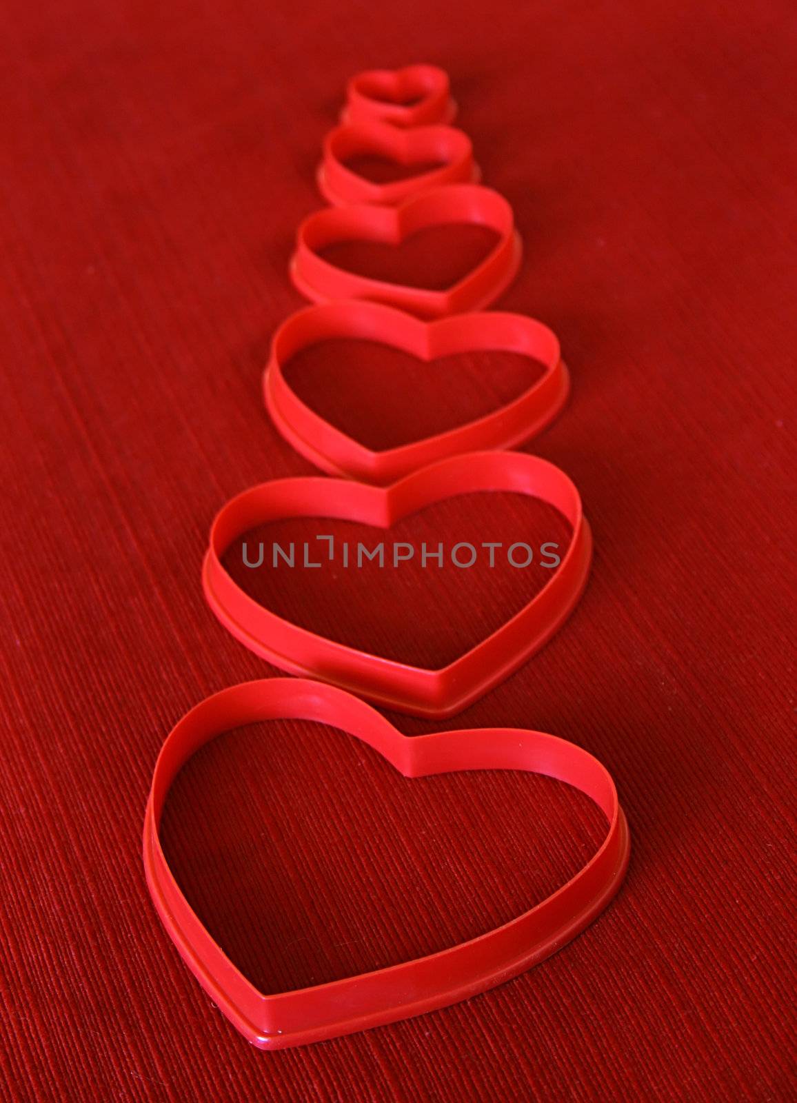 Cookie cutter hearts lined up on a red background.

