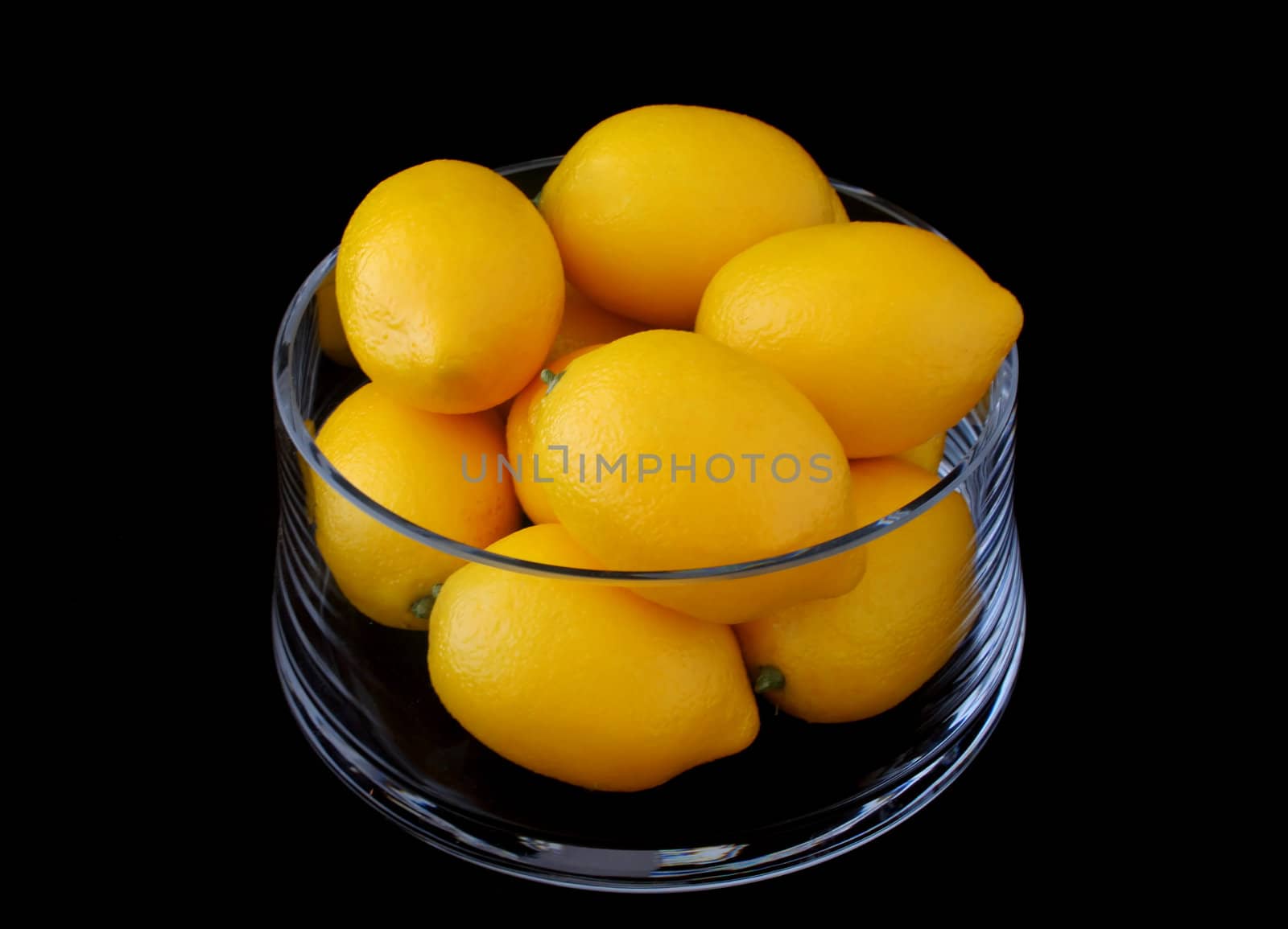 Lemons in a crystal bowl on a black background.

