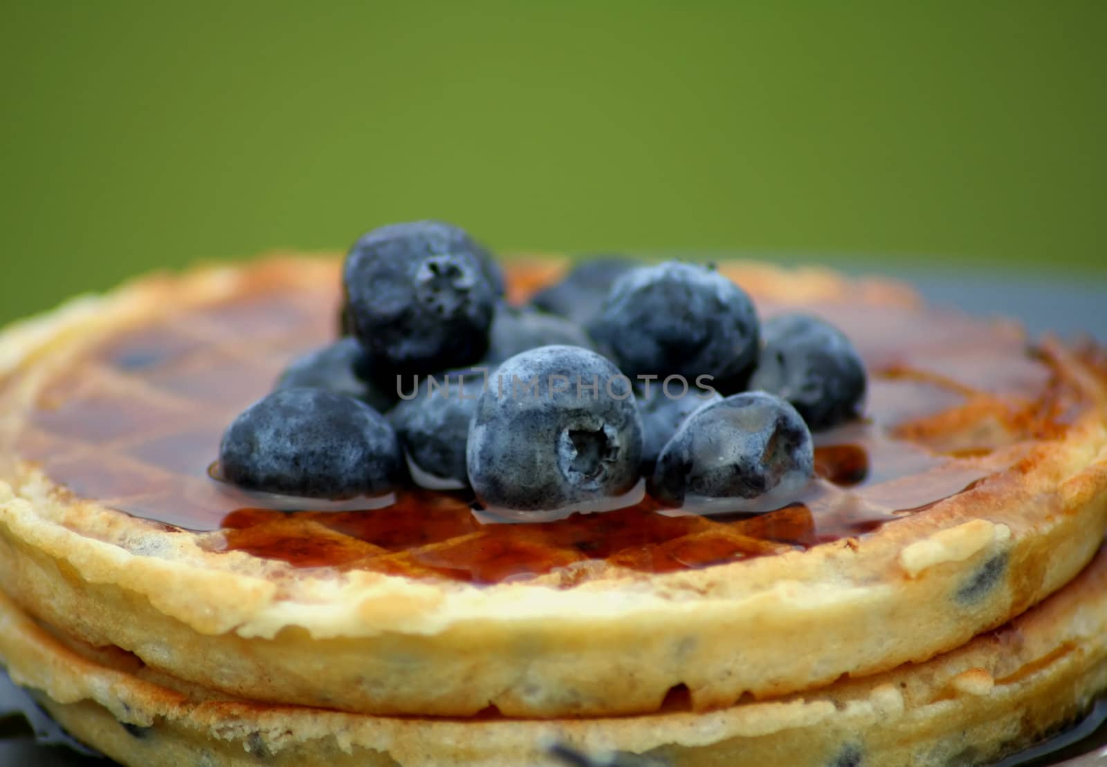 close up of delicious blueberry waffles topped with fresh blueberries and syrup
