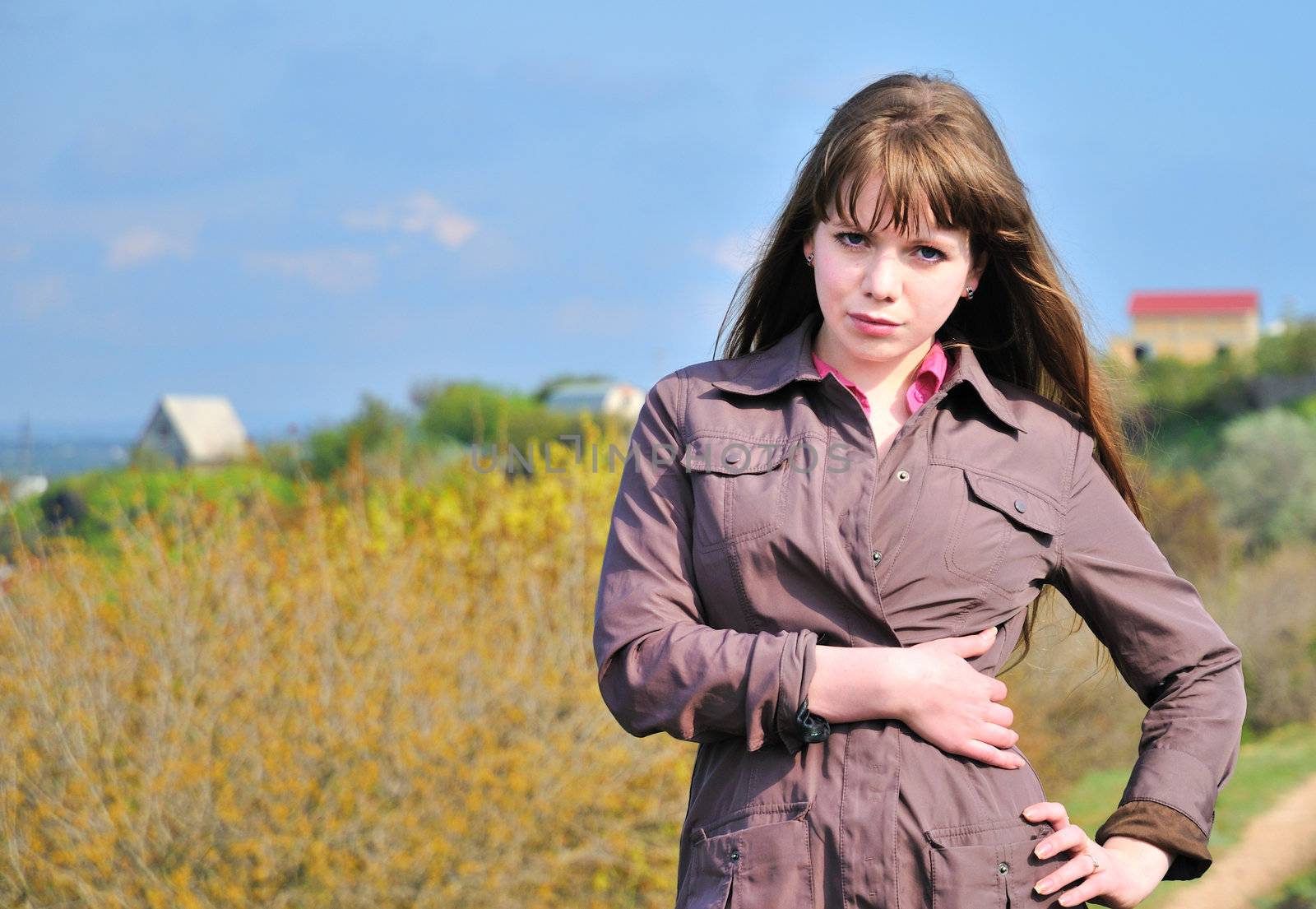 Fashion model standing and looking at the camera over countryside