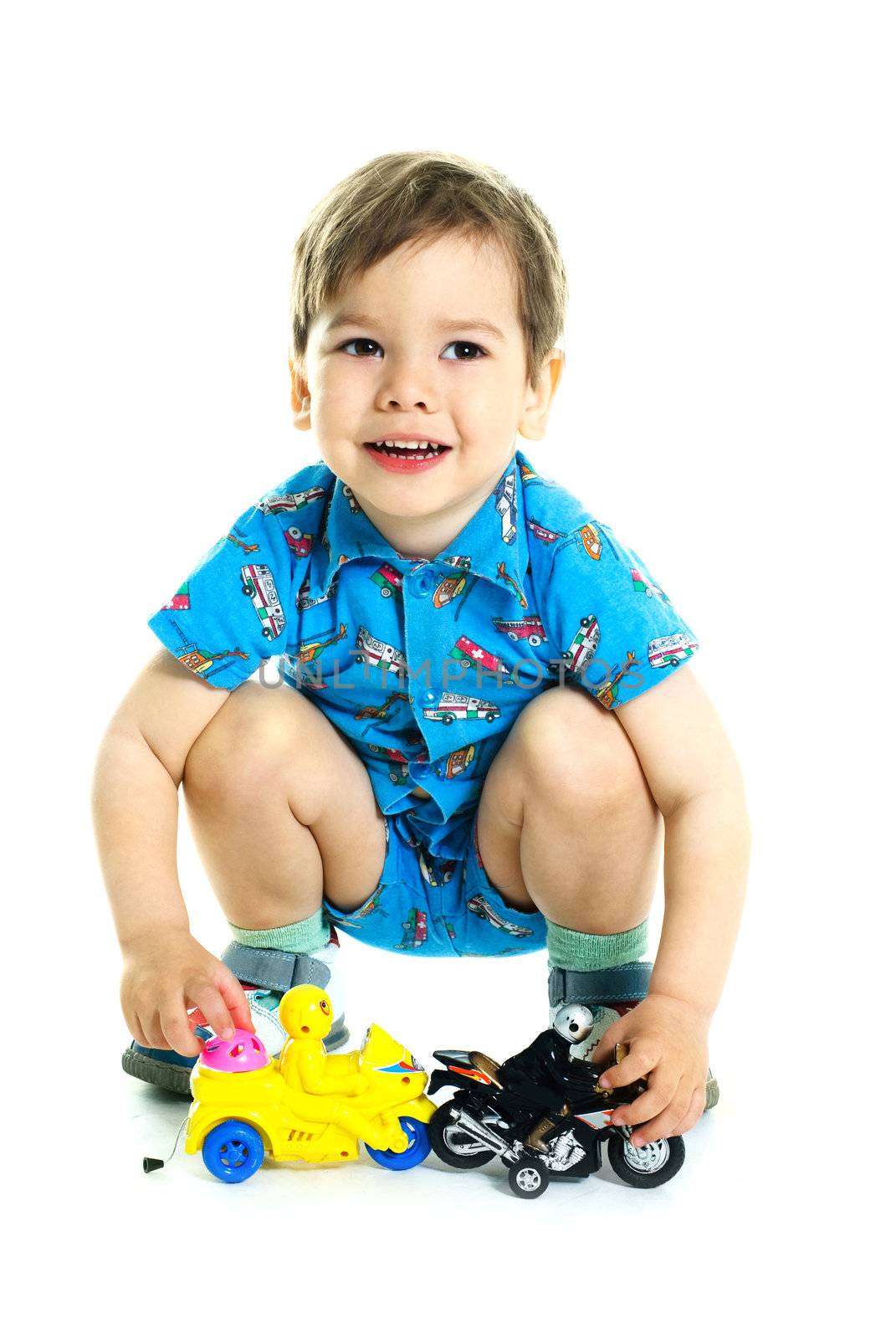 portrait of a cute happy three year old boy playing with toy motorcycles