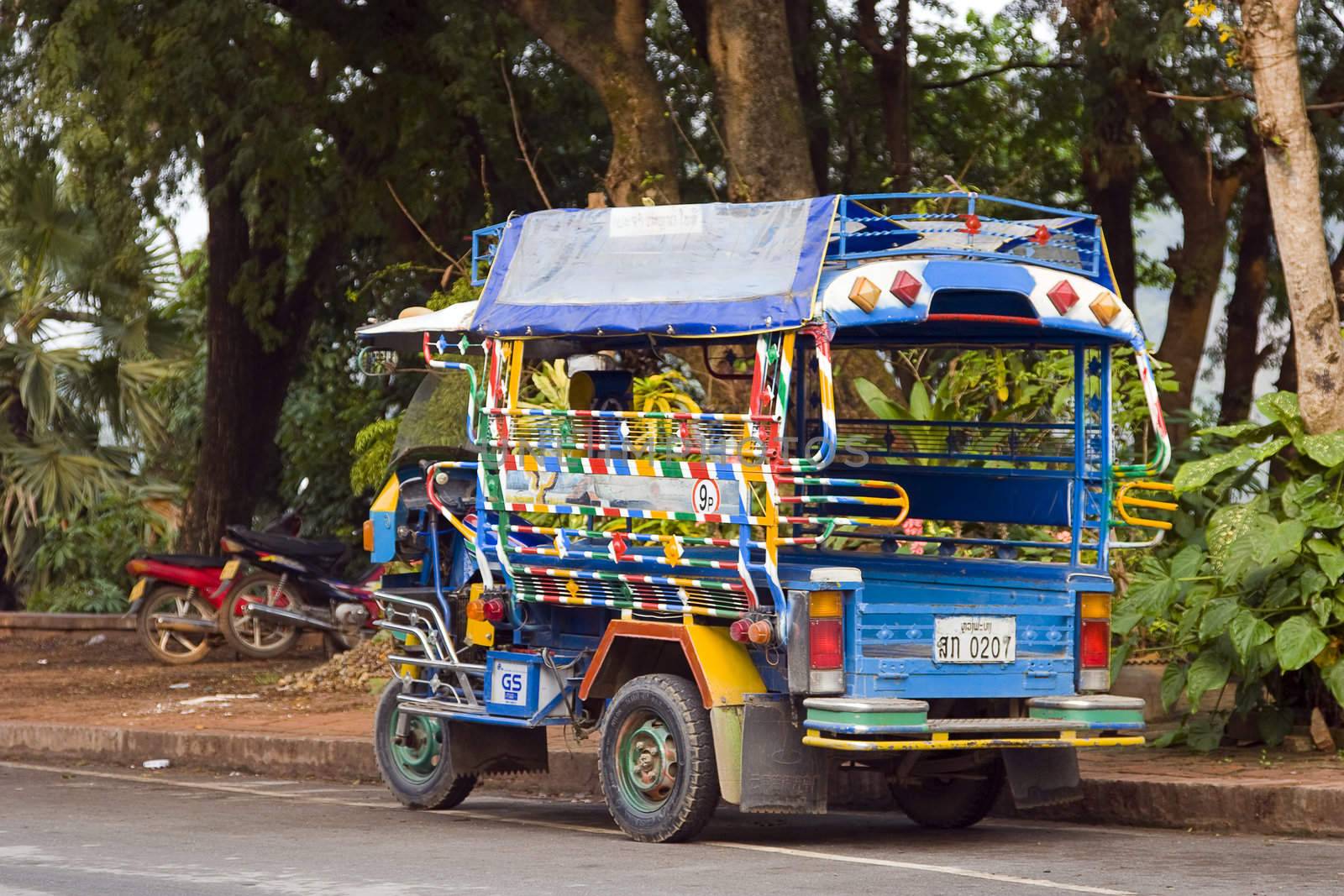 A Laotian tuk-tuk. Colorful and attractive, the owner has to do what he can to attract customers. These tuk-tuks are allowed to seat 9 people. 