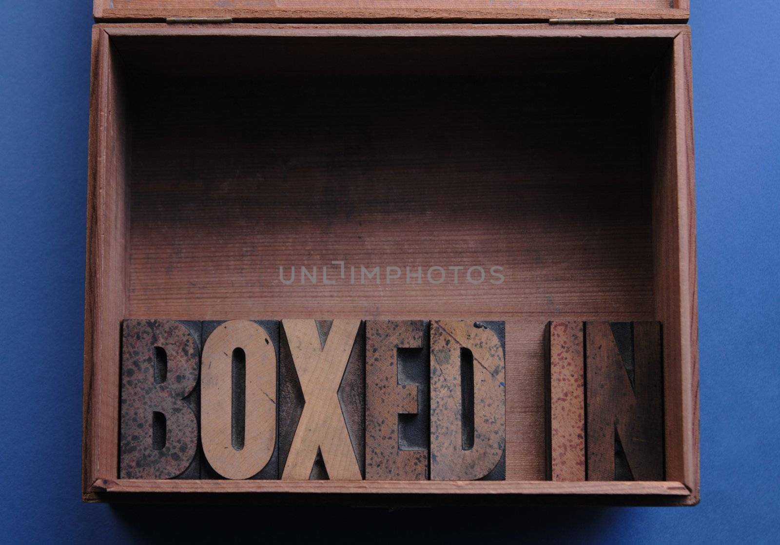 the phrase 'boxed in' in wood type inside a wood box