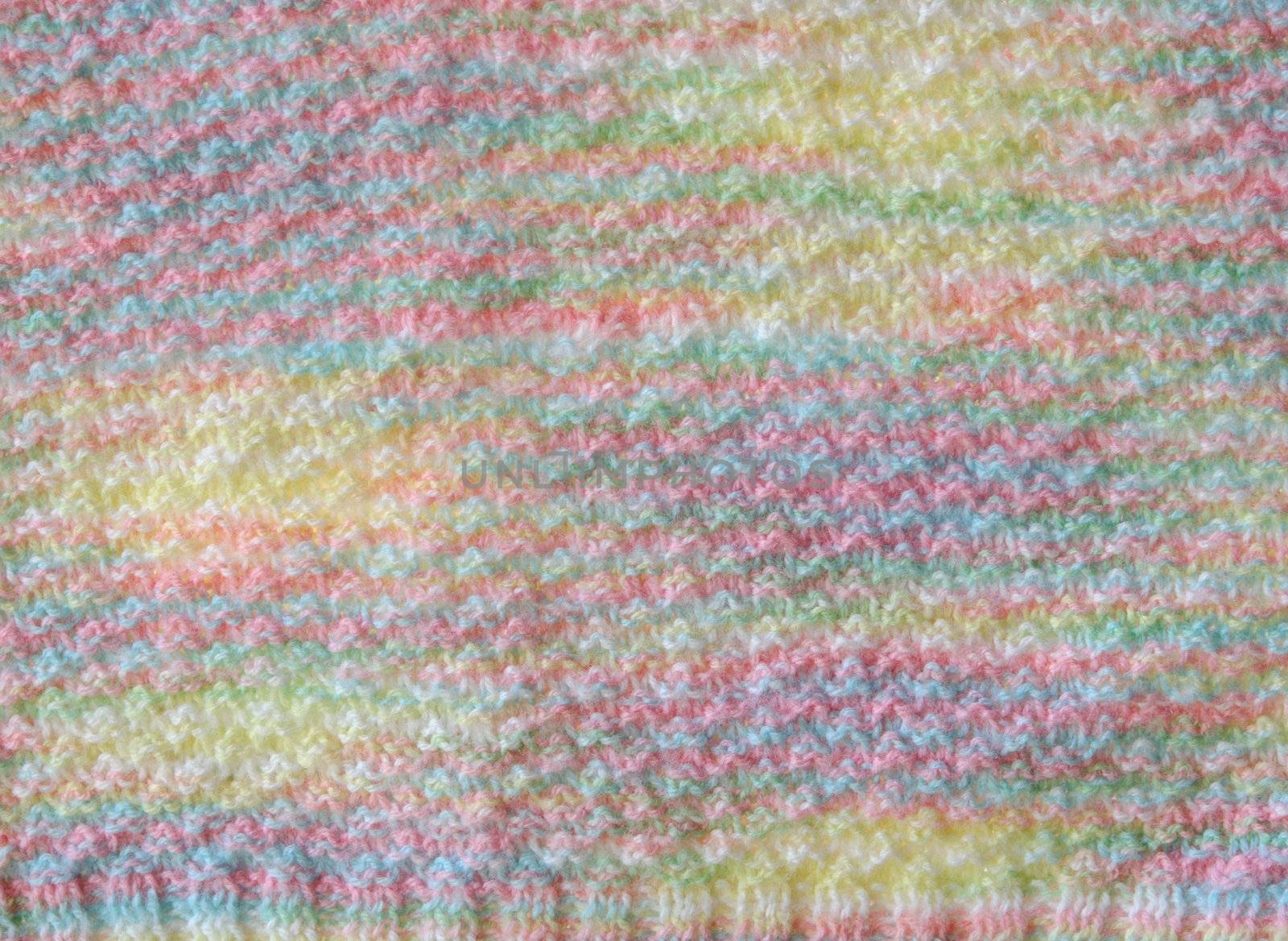 close-up of a soft hand-knit sweater in pastel shades of yellow, blue, pink and green