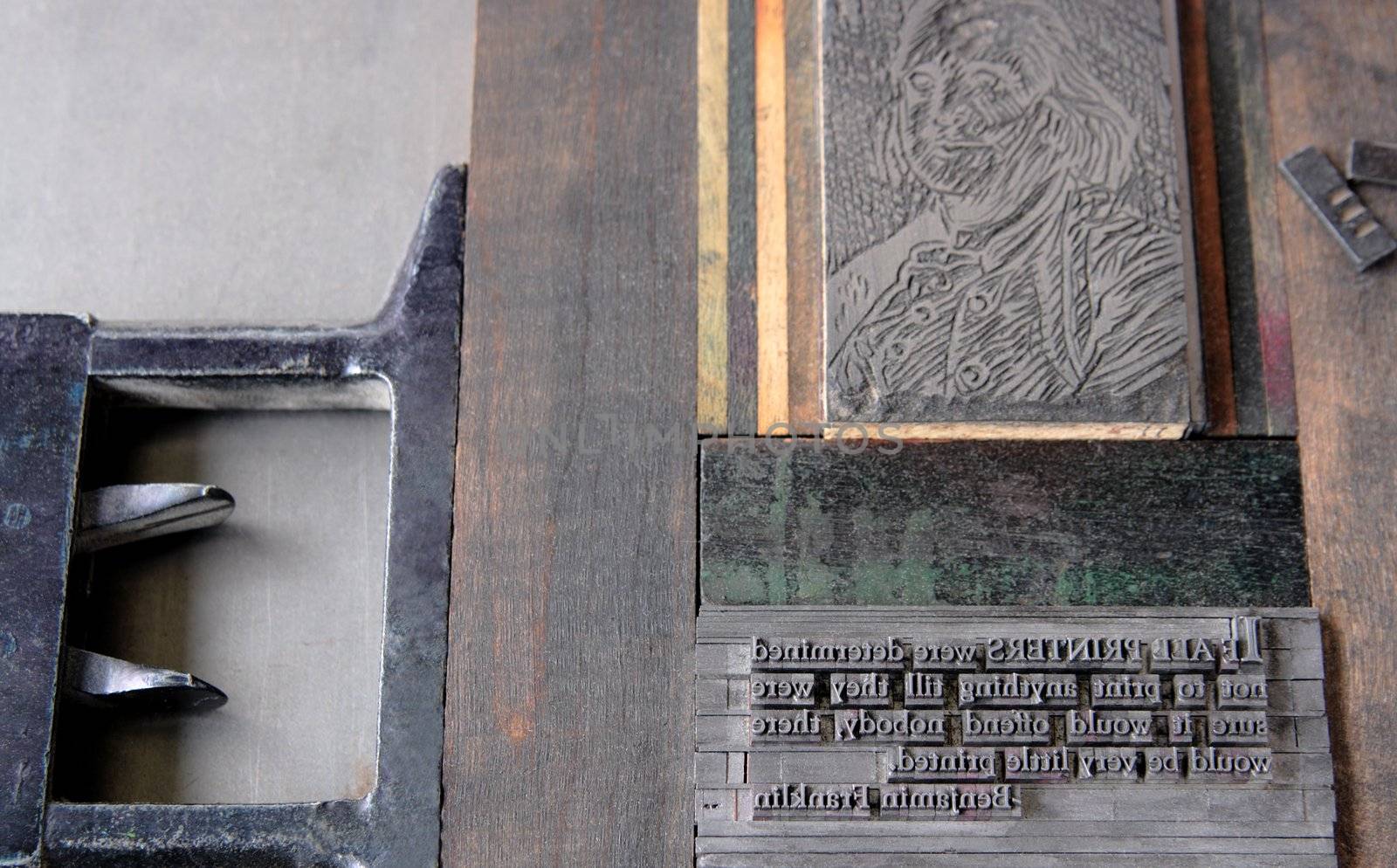 a printer's tray holds a quote from Benjamin Franklin in lead type with a linoleum cut of Franklin